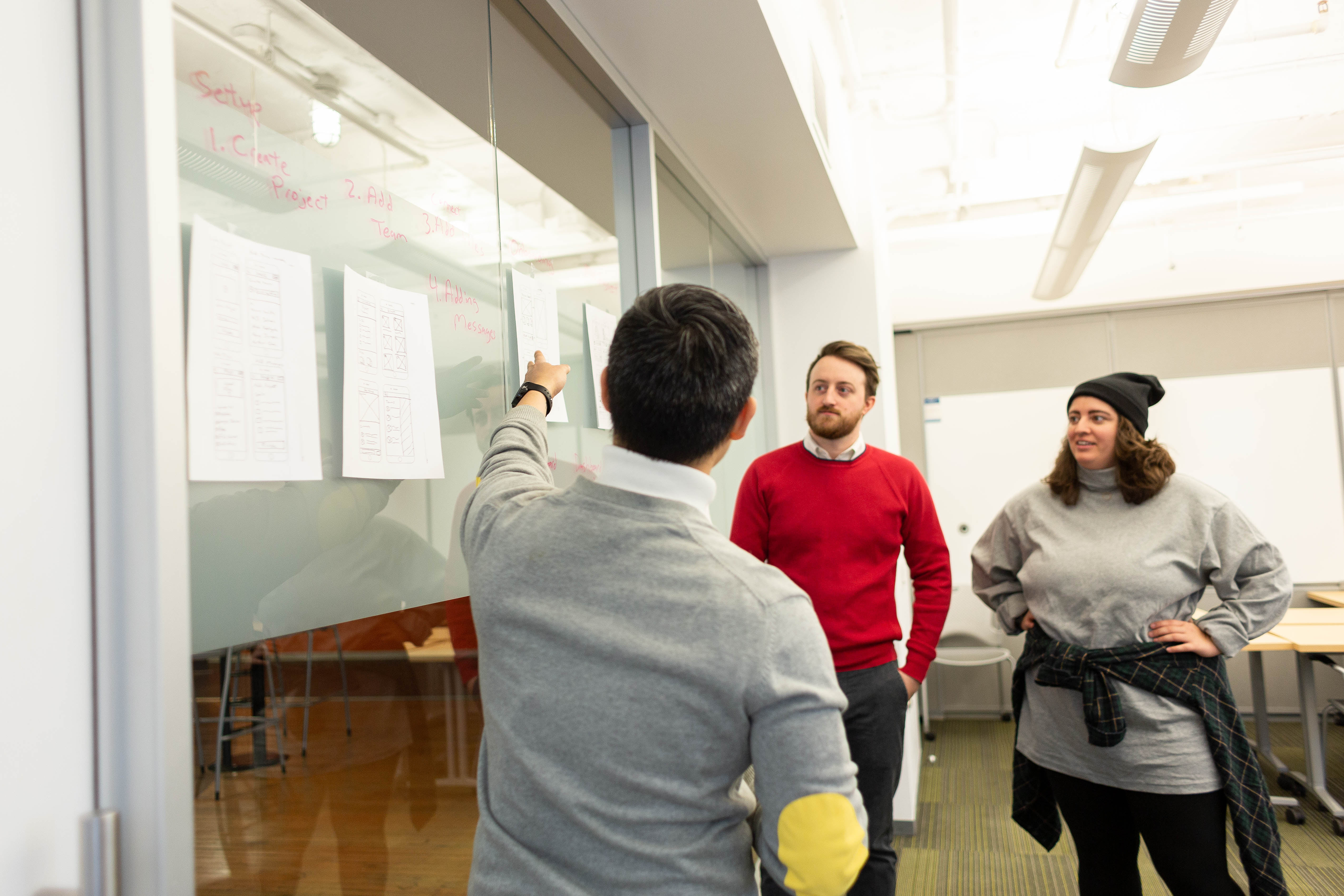 Team discussing sketches at a glass wall
